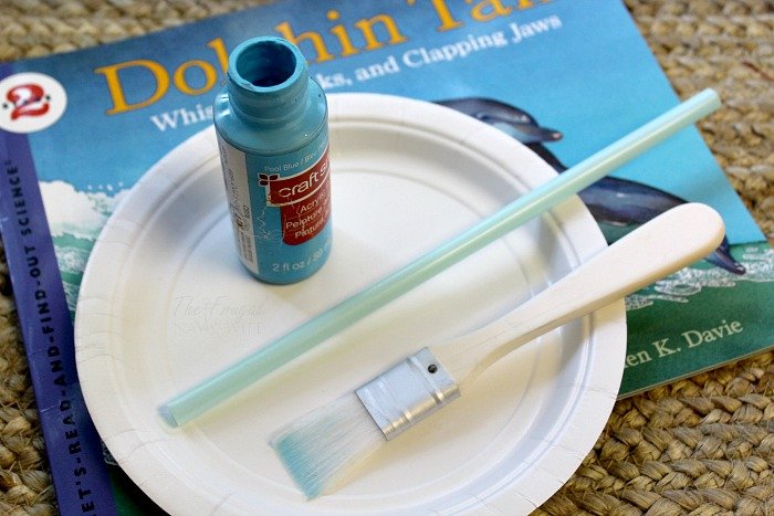 Paper plate craft, blue paint, straw, paint brush and dolphin talk science book. 